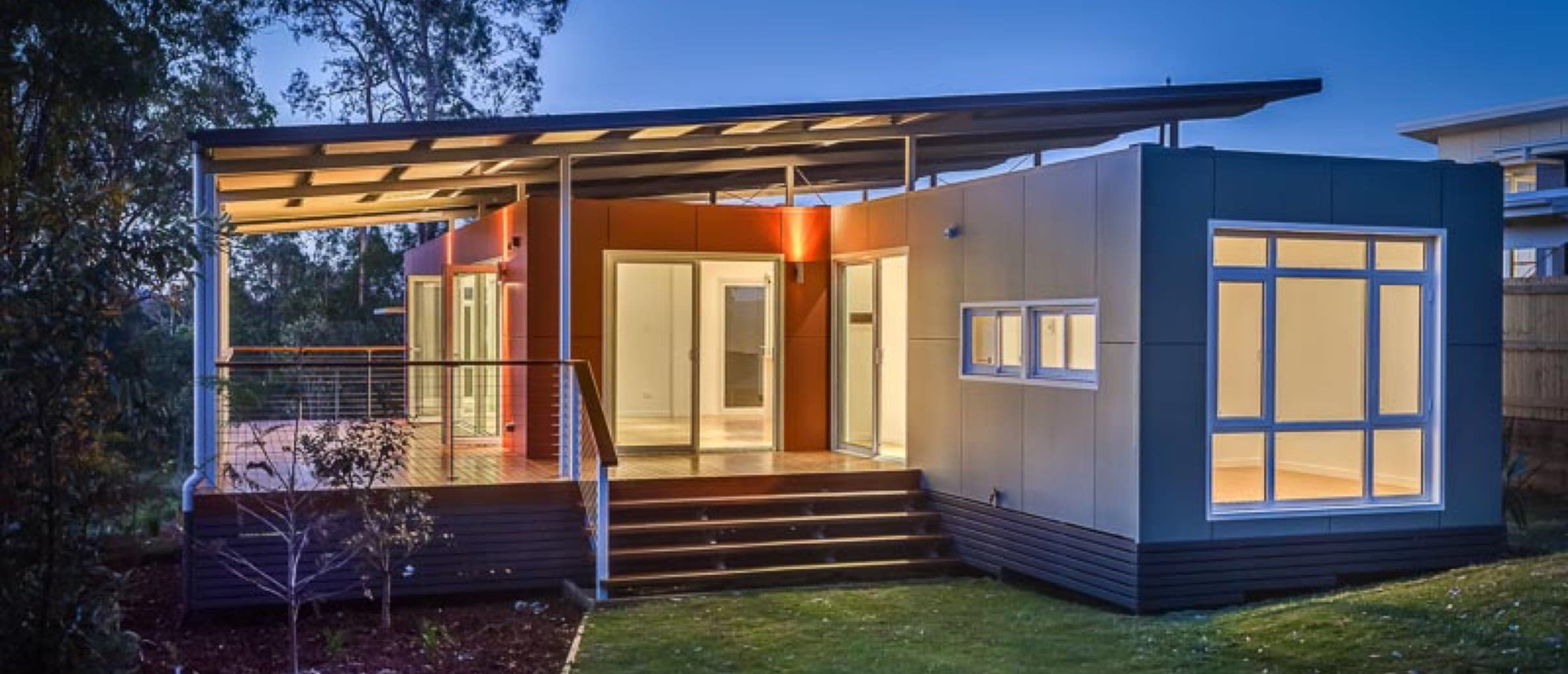 A 6Homes Dawson at twilight, interior lit, floating skillion roof
